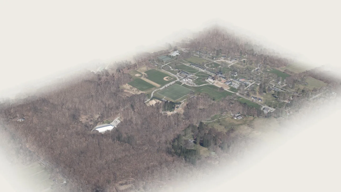A render of the real 2023 LiDAR and aerial survey: the Pomfret School campus on its hill seen from high above, playing fields and buildings among bare April woods.