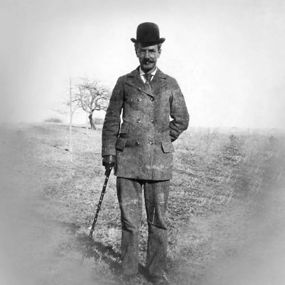 William E. Peck, Pomfret's founder and first headmaster, standing in a field in a bowler hat with a walking stick, 1890s